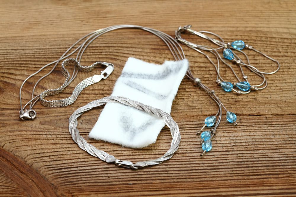 A close-up photo of a person cleaning a sterling silver bracelet with a polishing cloth.