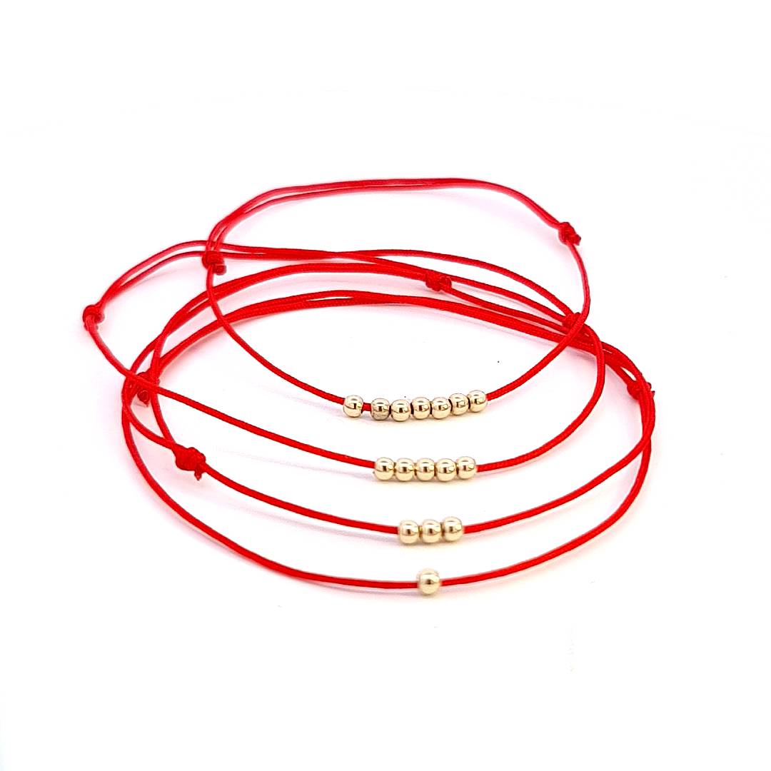 Zoomed-in photos of the bracelets, focusing on the quality of the gold beads and the texture of the red string to highlight craftsmanship and material excellence.