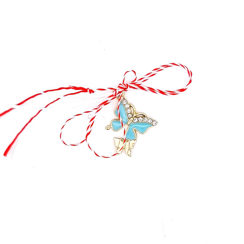 Gold-plated Martisor charm with blue enamel butterfly, symbolising wisdom and freedom, tied with red and white string.