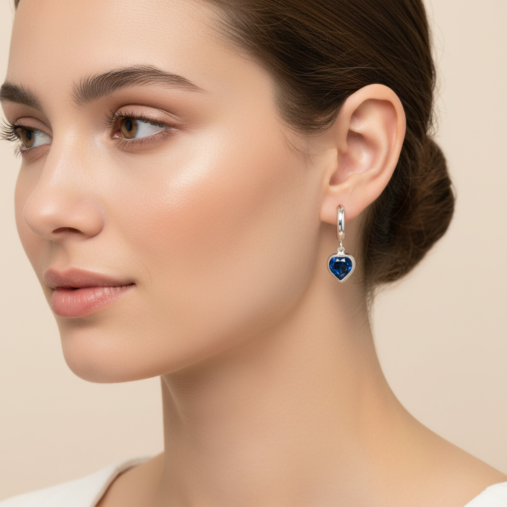Model wearing sterling silver hoop earrings with December birthstone Montana blue heart crystal charm – Magpie Gems in Ireland.