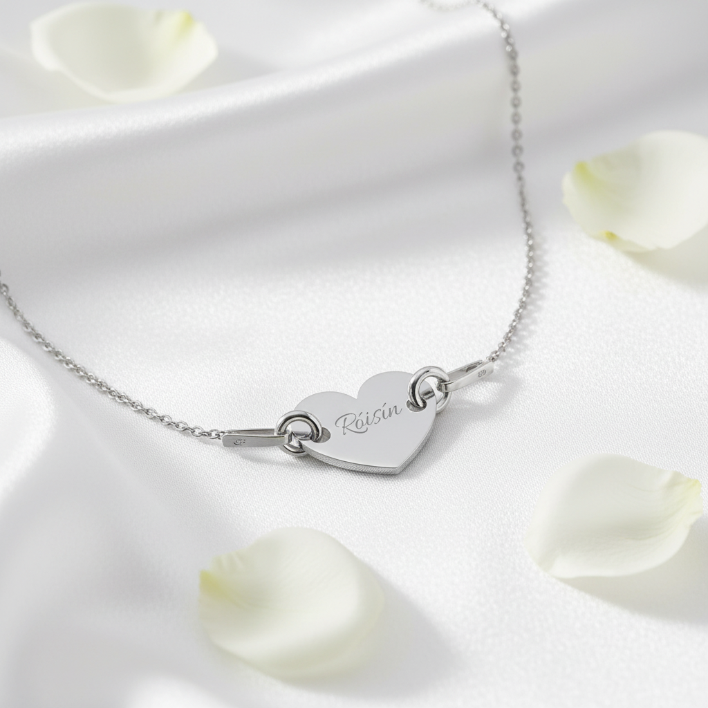 Silver heart-shaped bracelet with engraved name on a white surface with flower petals