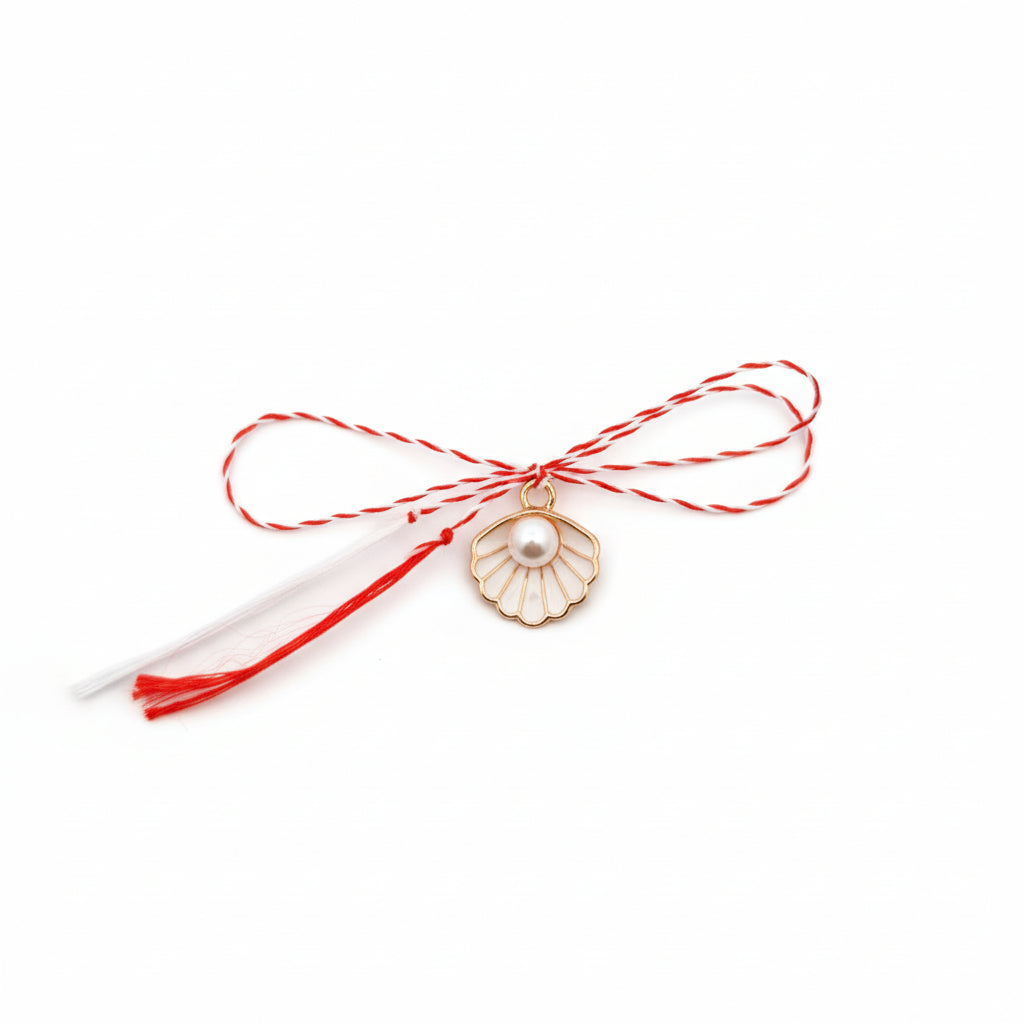 Mărțișor charm featuring a delicate shell design with pearl detail, tied with traditional red and white string, handcrafted by Magpie Gems in Ireland.