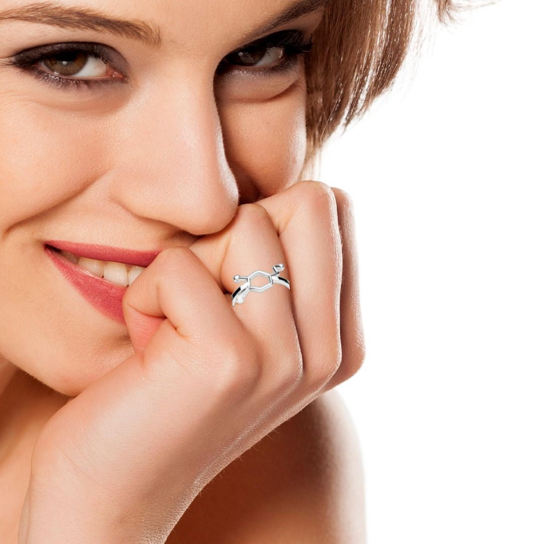 Close-up of a woman's hand showcasing the Silver Dopamine Molecule Ring from Magpie Gems, reflecting its lustrous finish and unique chemical structure design.