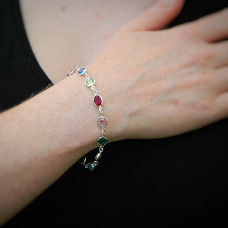 Woman wearing a Sterling silver bracelet with multi-colored birthstone crystals