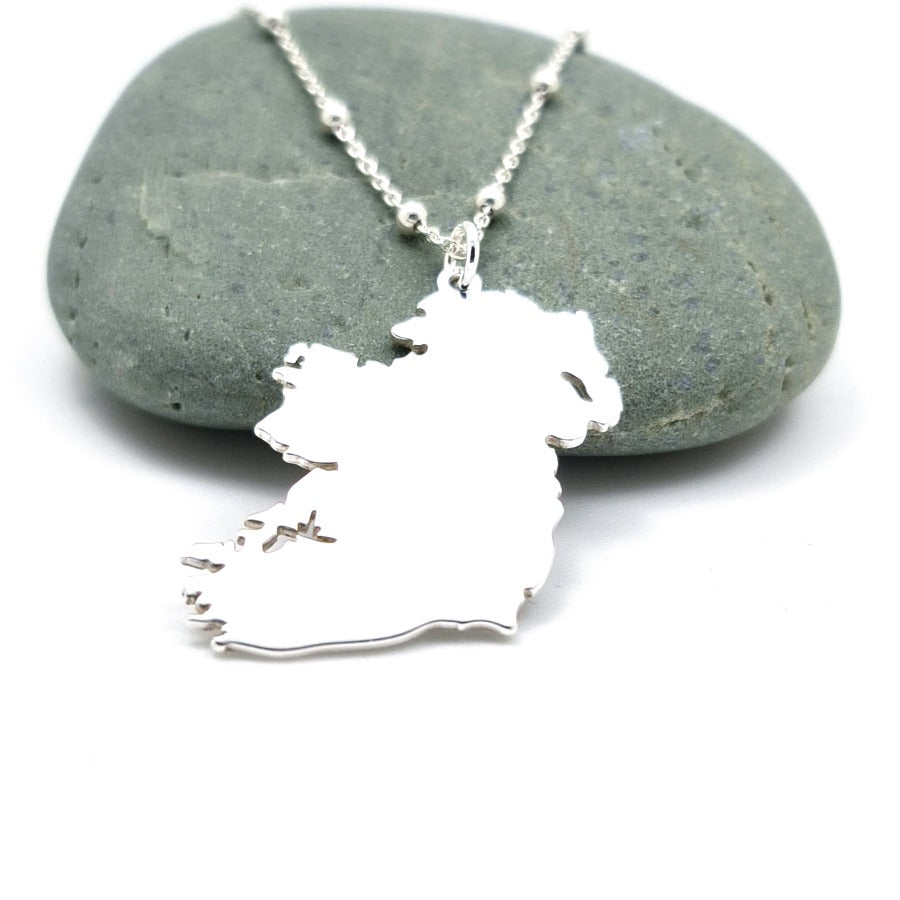 Silver Eire Ireland Map pendant necklace with ball chain on an Irish rock