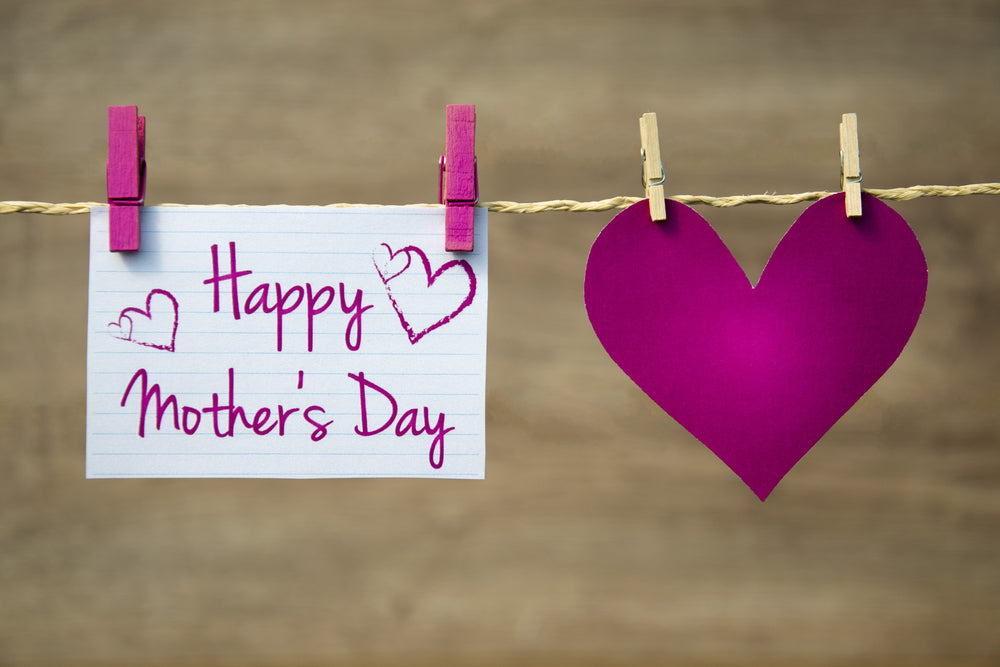 A heartwarming display for Mother's Day featuring a large heart and a handwritten note that reads "Happy Mother's Day" attached to a string with pegs. The heartfelt display is a beautiful reminder of the love and appreciation we have for our mothers.