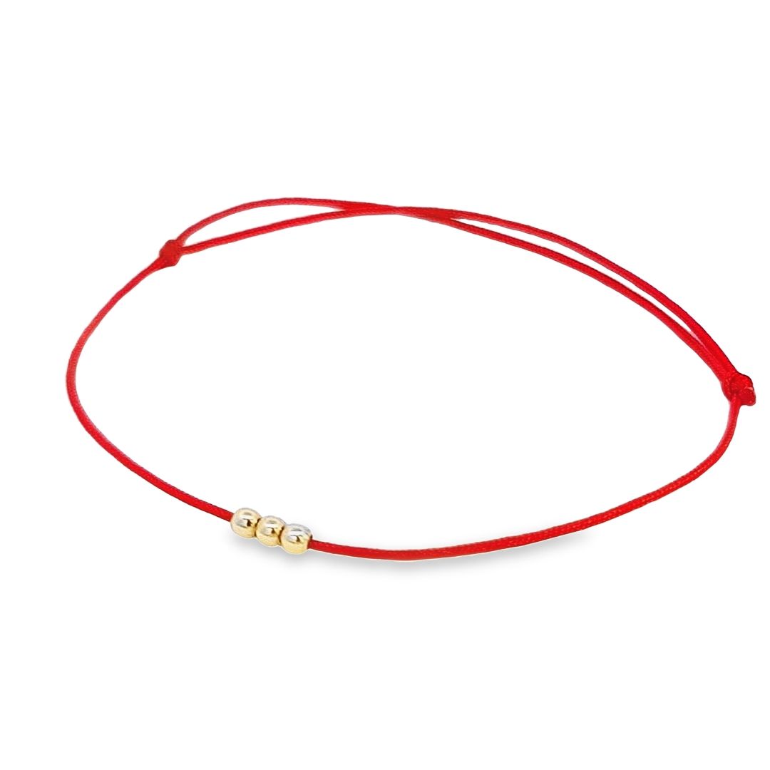 Another angle of the adjustable red string bracelet, highlighting the spacing between the trio of 14k gold beads.