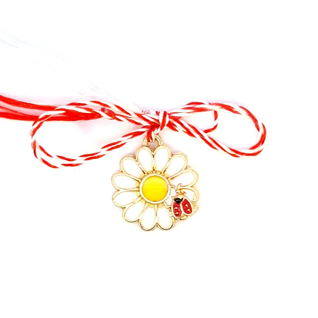 Close-up of the 'Sunny Bloom' Martisor charm with a bright white and yellow enamel daisy and a red and black ladybug.