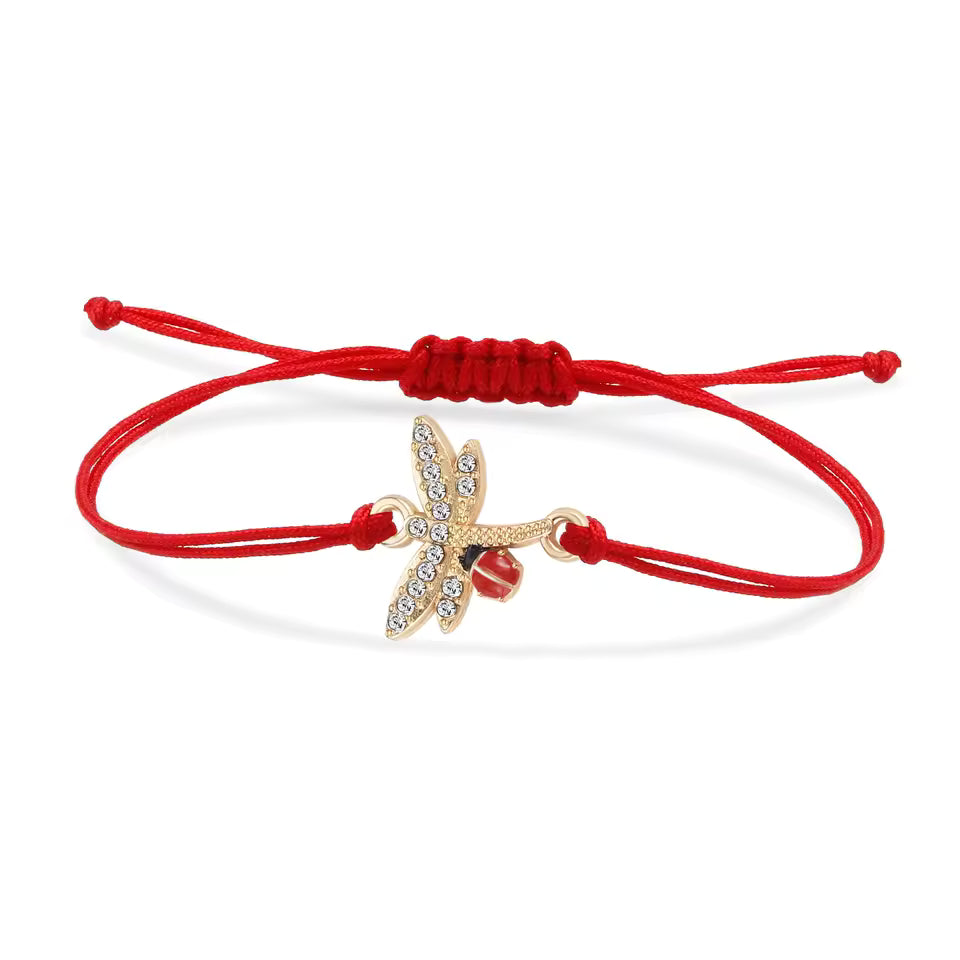 Gold dragonfly Mărțișor bracelet with adjustable red thread and ladybug, showcased against a white background.