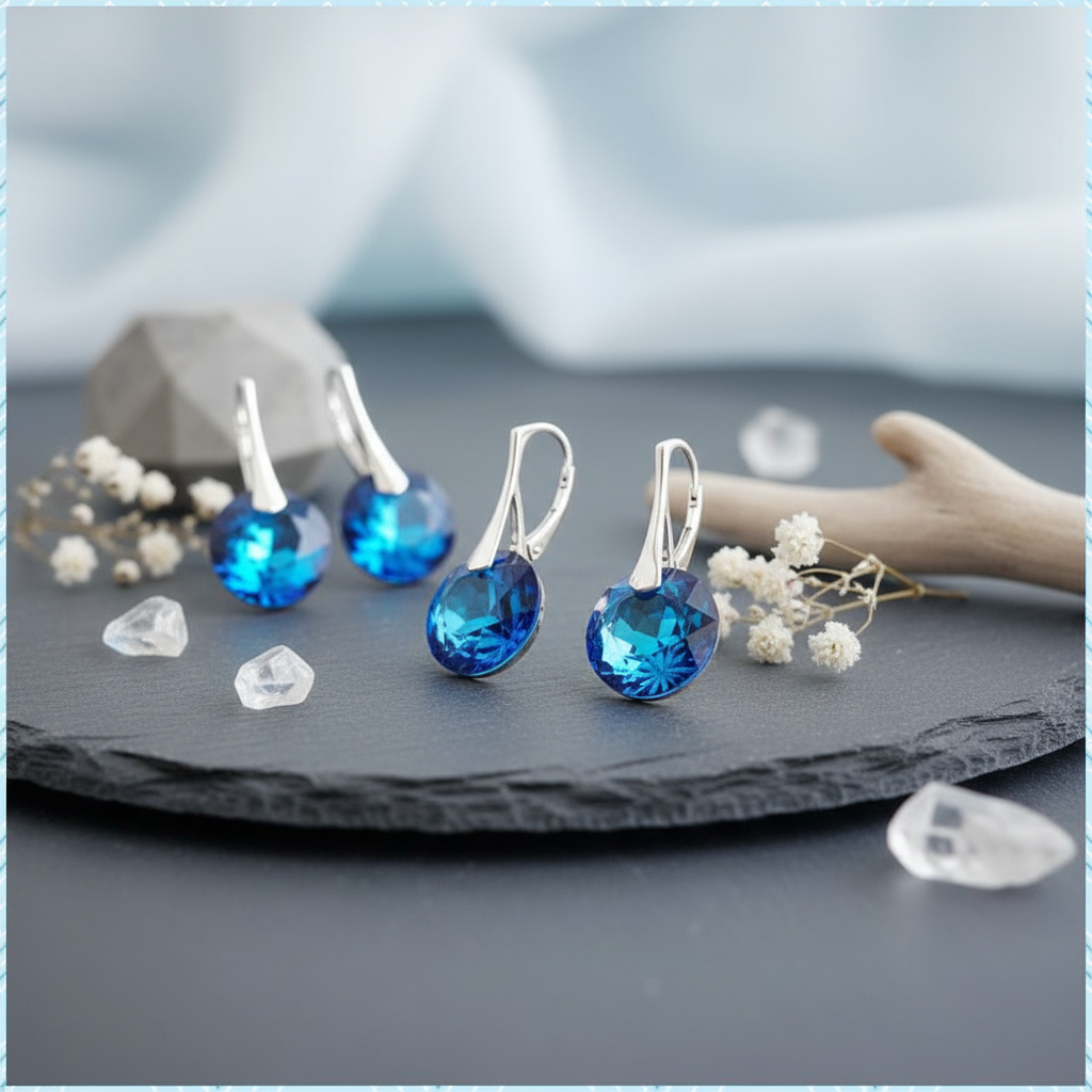 Blue crystal earrings on a dark surface with a blurred background