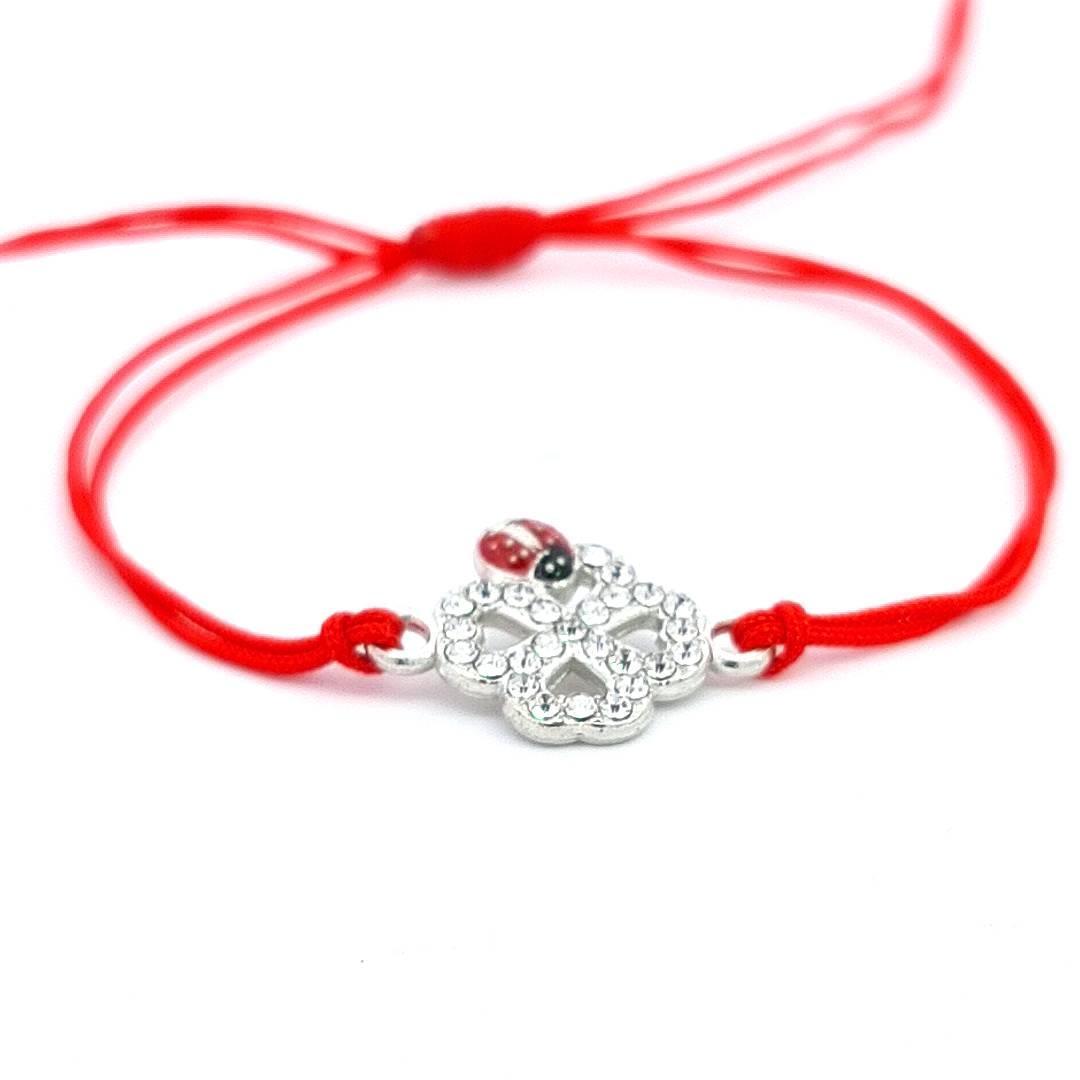 Elegant 'Ladybird Luck Clover' Martisor Bracelet with a shimmering crystal clover and red enamel ladybird on a red adjustable macramé cord, displayed against a white background.