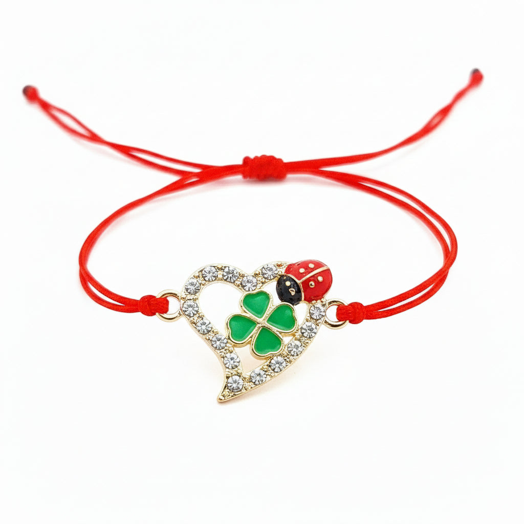 Elegant 'Luck and Love' Martisor Bracelet featuring a gold-plated heart with crystal edges, green enamel four-leaf clover, and a red ladybird on an adjustable red cord. Friendship Bracelet made in Ireland