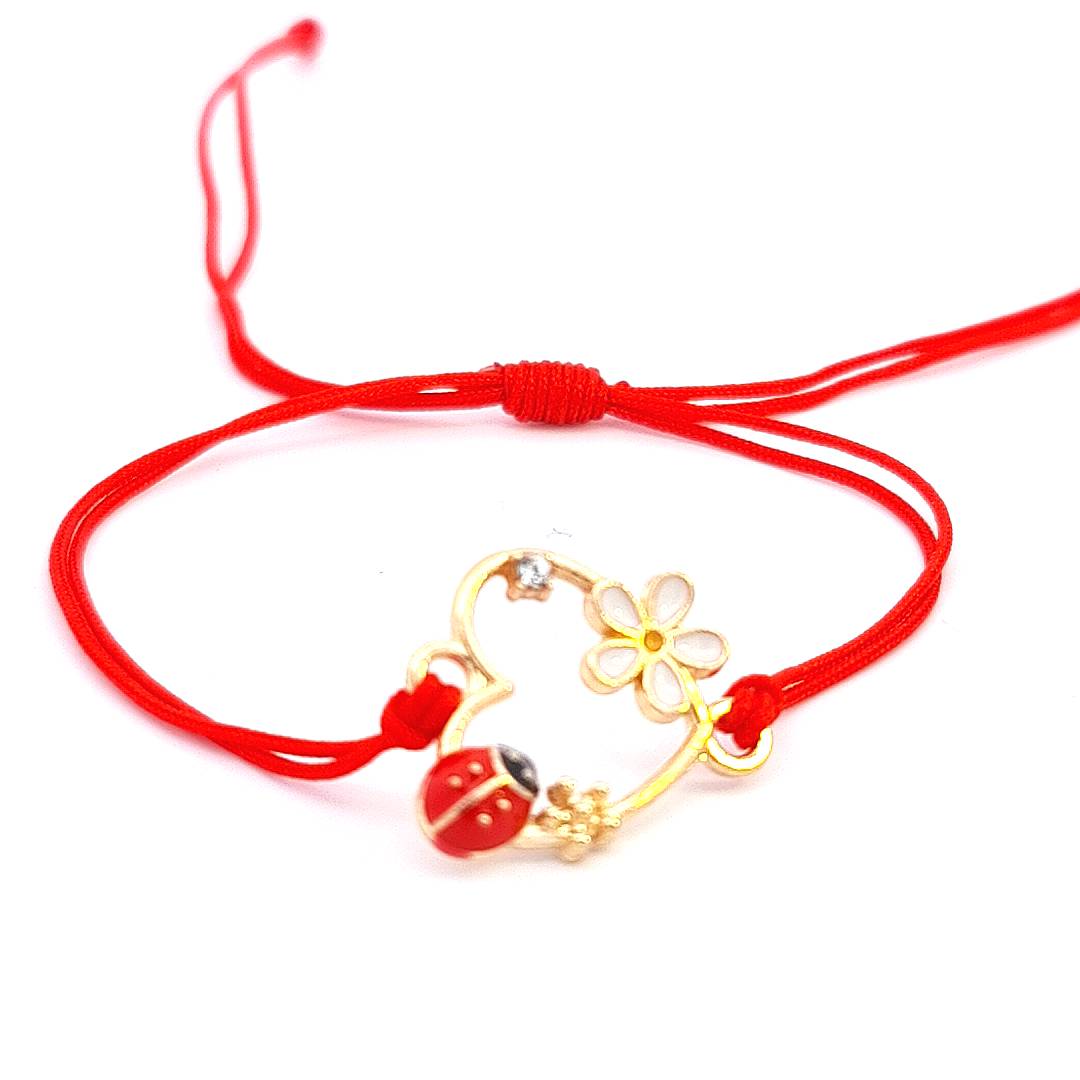 Detail of the 'Heartfelt Blossom' Martisor Bracelet highlighting the gold-plated heart, delicate flower, and enamel ladybird against the red macramé cord.