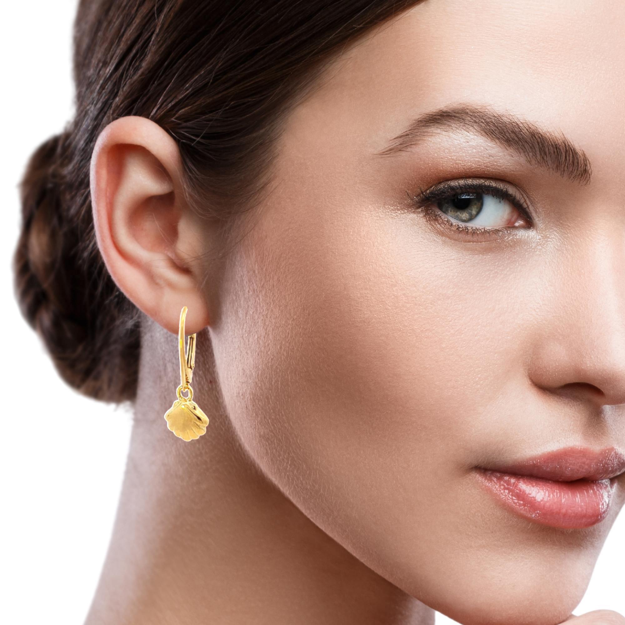 Brunette woman elegantly showcasing the Gold Shell Dangle & Drop Earrings from Magpie Gems' Ocean Collection.