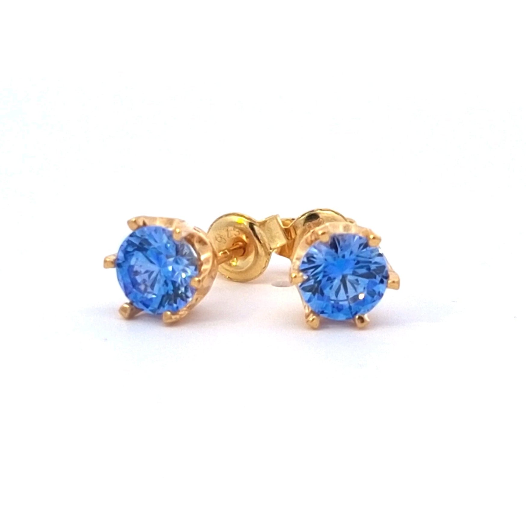 Gold stud earrings with blue gemstones on a white background