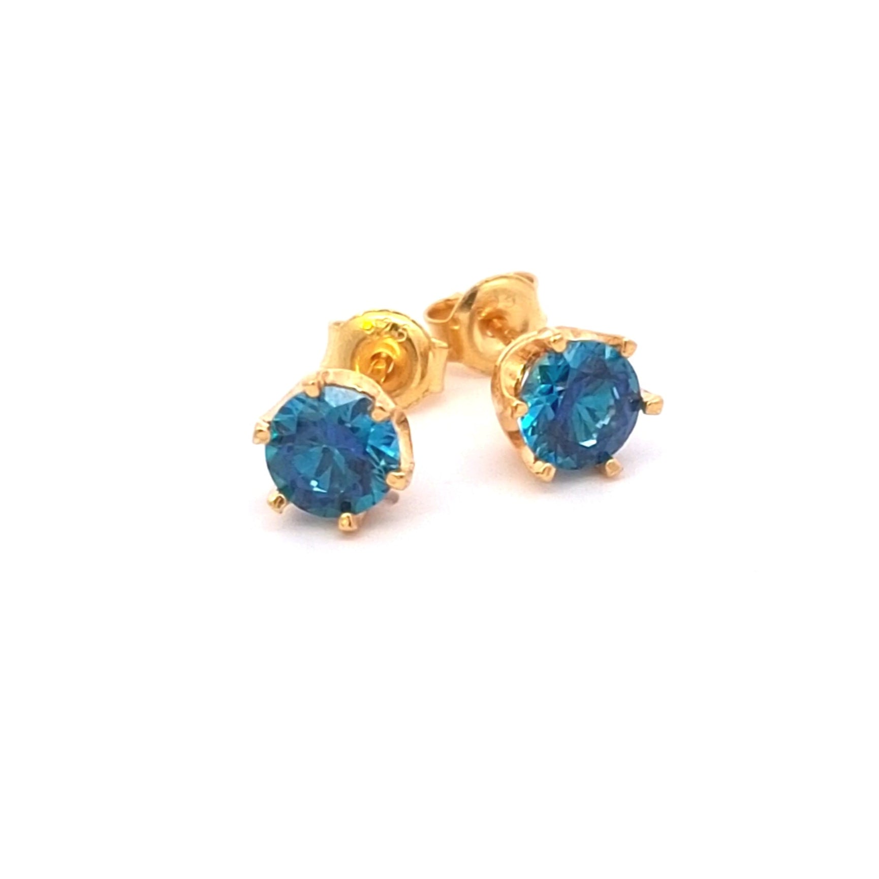 Gold earrings with blue gemstones on a white background. Ocean blue Cubic Zirconia earrings in 24k gold-plated setting