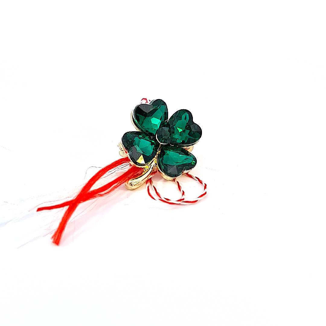 'Jade Radiance' Martisor brooch, depicting a rich green clover, attached to a storytelling card that narrates the legend of Martisor.