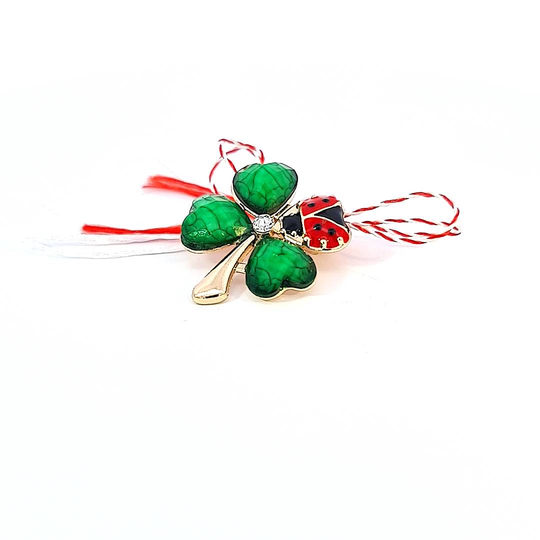 Close-up of the 'Verdant Sparkle' Martisor brooch with a central rhinestone and green enamel clover leaves and a ladybug.