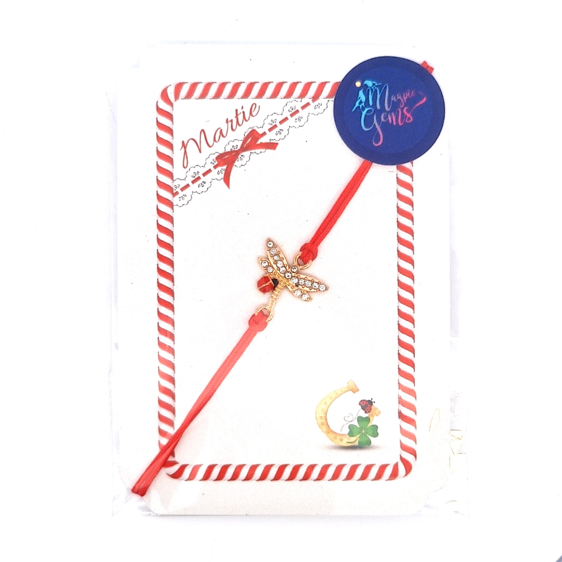 Whispers of Spring Mărțișor bracelet with gold dragonfly charm on red thread, presented on card with Magpie Gems logo.