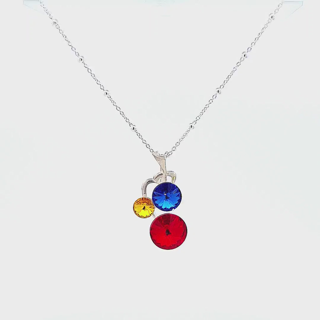 Video showcasing Harmony of Heritage Necklace with Red, Yellow, Blue Crystals, on White Background and Woman Wearing It
