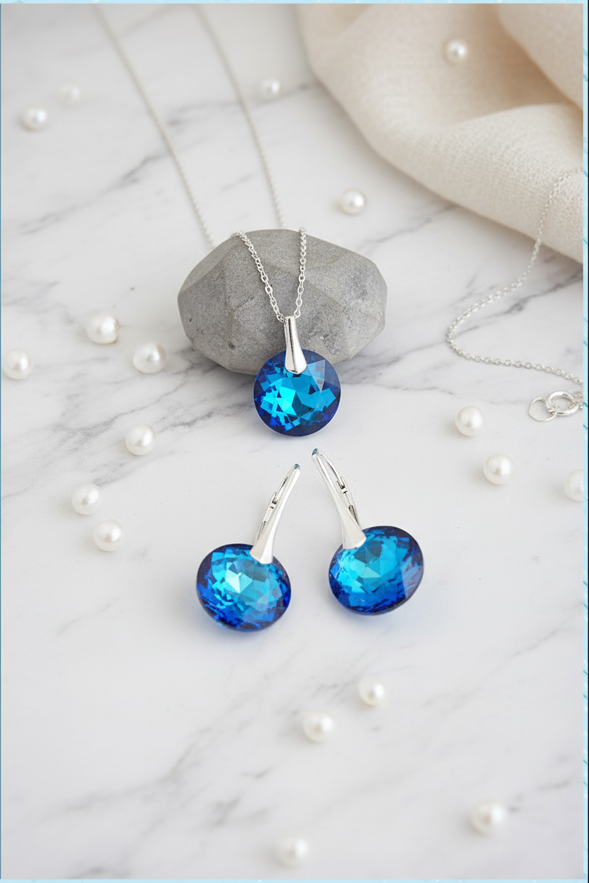 Blue gemstone necklace and earrings on a marble surface with pearls.