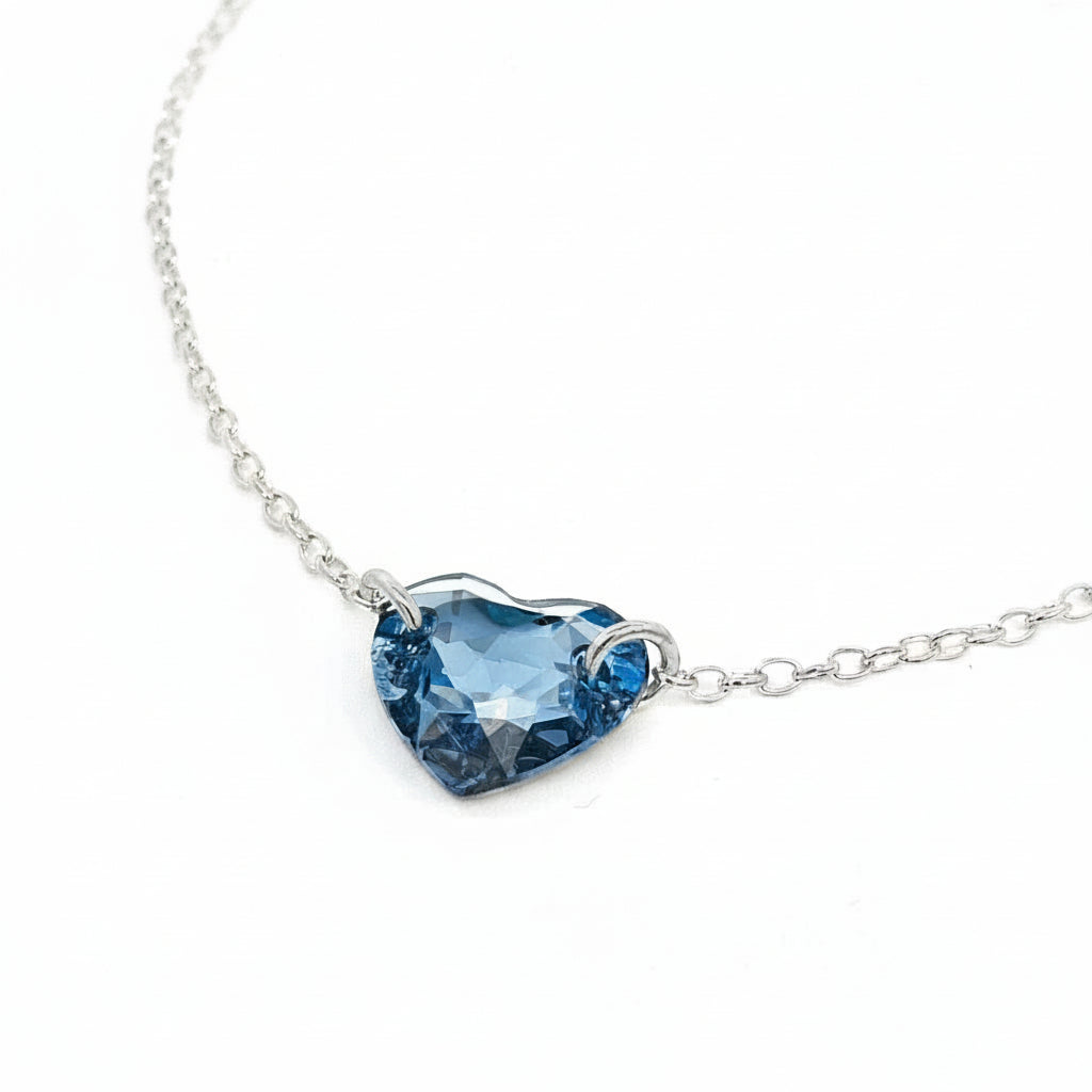 Close-up of feet with silver anklet with denim blue crystal heart on a wooden deck