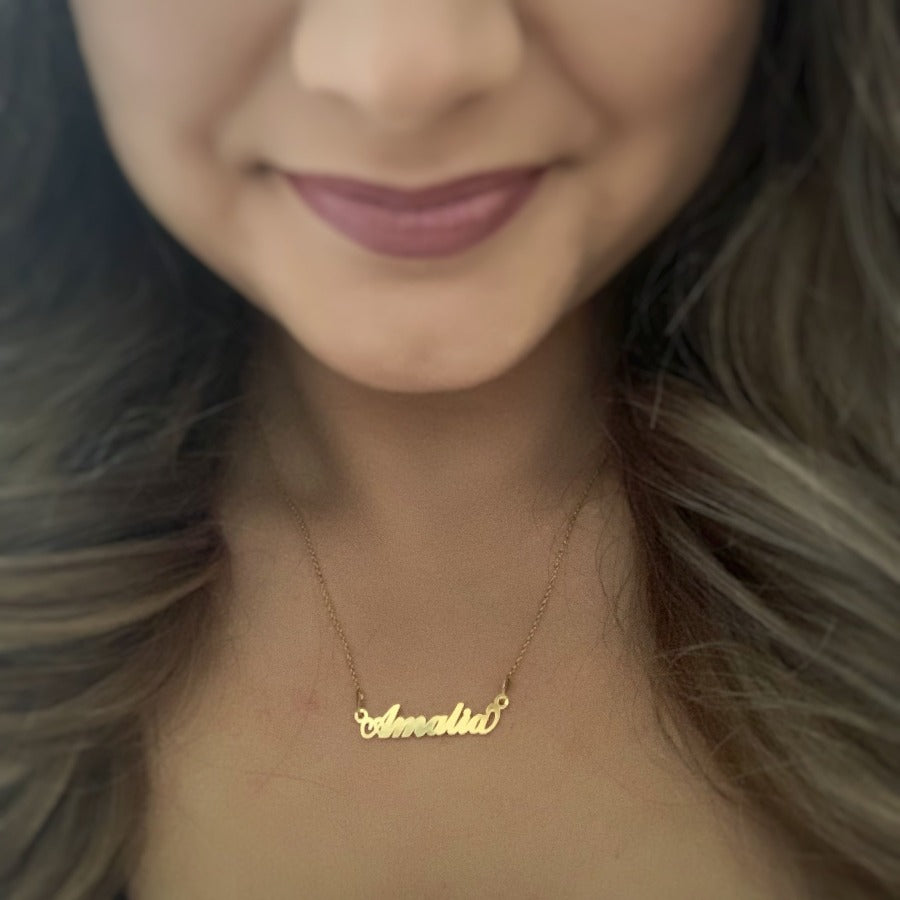 Image of a woman wearing a personalized name necklace in 24k gold plated nickel-free sterling silver, featuring a delicate chain and a laser-cut pendant with her chosen name or word on it in Ireland