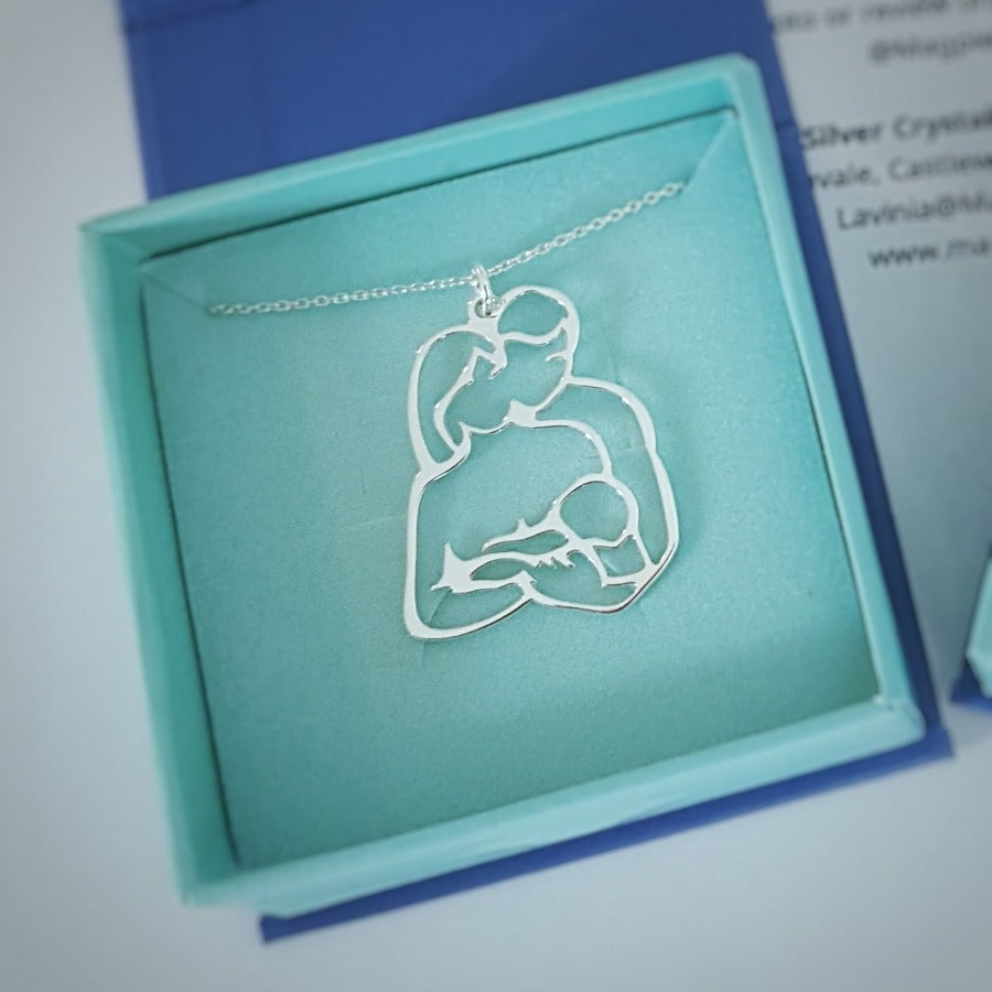 Unconditional Love Silver Necklace in a gift box, a Father and Mother Silver Necklace with pendant featuring a father holding a mother who is breastfeeding a baby, made of nickel-free sterling silver by Magpie Gems, online jewellery shop in Cork Ireland