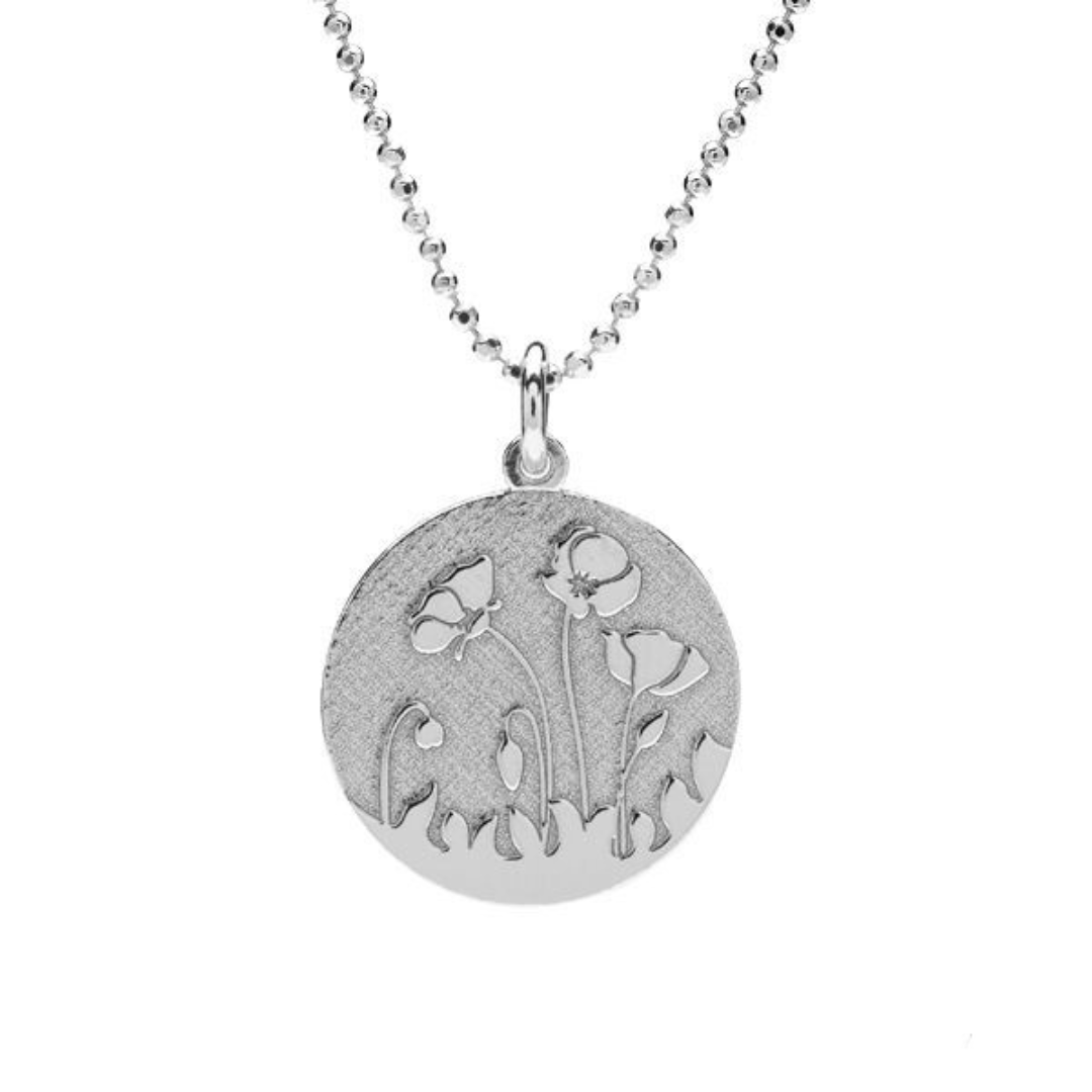 A close-up of the delicate poppy disc necklace in nickel-free sterling silver on a fine ball chain from Ireland.