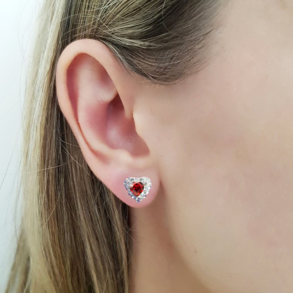 Women wearing a heart shaped stud earring in sterling silver, with a garnet red central heart crystal and tiny moonlight crystals around it, in a pave style heart earring, made in Ireland by Lavinia of Magpie Gems Jewellery in Cork.