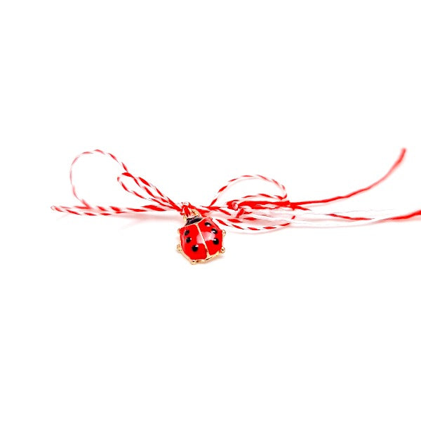 A small and dainty ladybug charm Martisor with red and wite string, offered to children or women on 1st of March, a celebration of Spring arrival from Romania and Eastern European cultures.